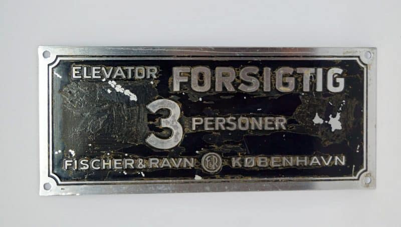 Elevatorskilt. 3 Personer. Forsigtig. Fischer & Ravn København