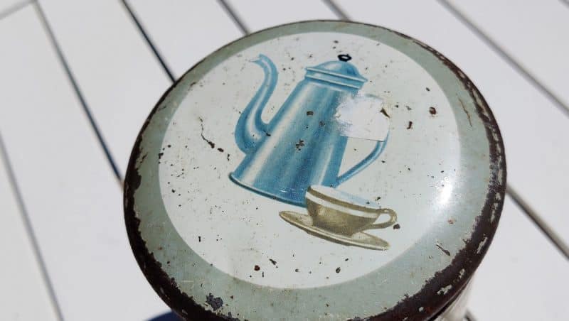 Kaffedåse med plantagearbejdere og madamblå på toppen