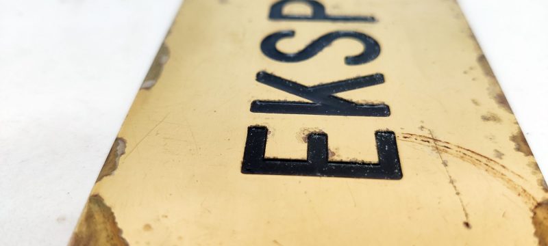 Messing skilt med nedfræset tekst: Ekspedition