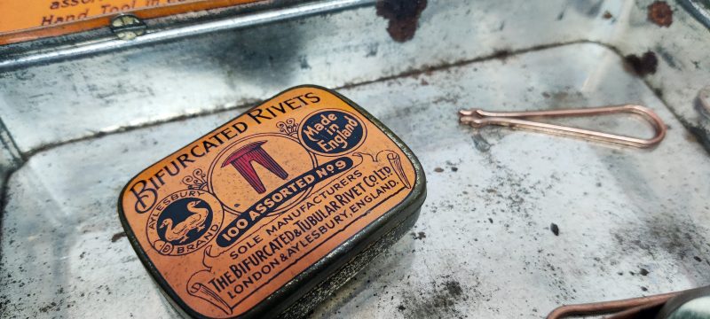 Bifurcated Rivets (Kobber nitter). Engelsk salgsstander i form af stor blikdåse med 2 mindre dåser