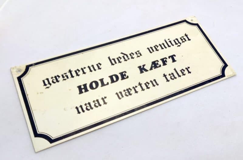 Gæsterne bedes venligst HOLDE KÆFT naar værten taler. Ældre humørskilt (1980erne)