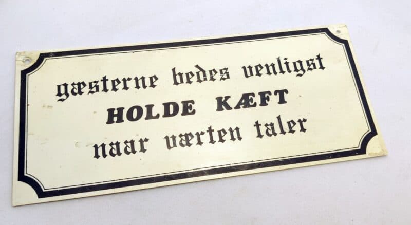 Gæsterne bedes venligst HOLDE KÆFT naar værten taler. Ældre humørskilt (1980erne)