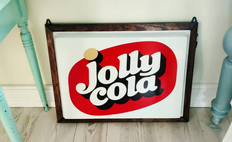 Jolly Cola lysskilt i plast. I træramme