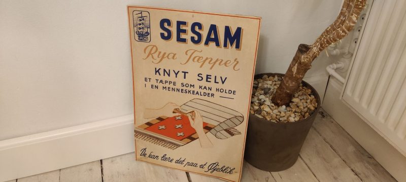Papskilt. Reklame for Sesam Rya Tæpper - Knyt selv - et tæppe som kan holde i en menneskealder. Det kan lære det paa et Øjeblik