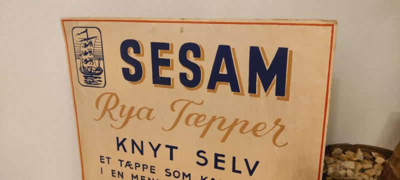 Papskilt. Reklame for Sesam Rya Tæpper - Knyt selv - et tæppe som kan holde i en menneskealder. Det kan lære det paa et Øjeblik