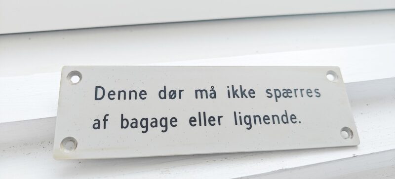 Denne dør må ikke spærres af bagage eller lignende. Sporvognsskilt