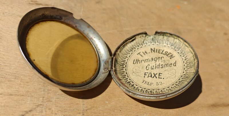 Th. Nielsen. Uhrmager og guldsmed Faxe.  Telf. 53. Blikdåse itui til lommeur med reklame