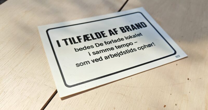 Humørskilt (plastik). I TILFÆLDE AF BRAND bedes de forlade lokalet i samme tempo - som ved arbejdstids ophør!