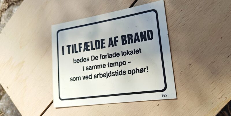 Humørskilt (plastik). I TILFÆLDE AF BRAND bedes de forlade lokalet i samme tempo - som ved arbejdstids ophør!